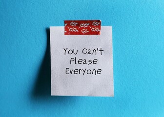 White note stick on blue background with handwritten text You Can’t Please Everyone - self...