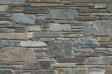 A sandstone masonry ashlar wall assembled with an aesthetic of irregular size stones is shown up close.