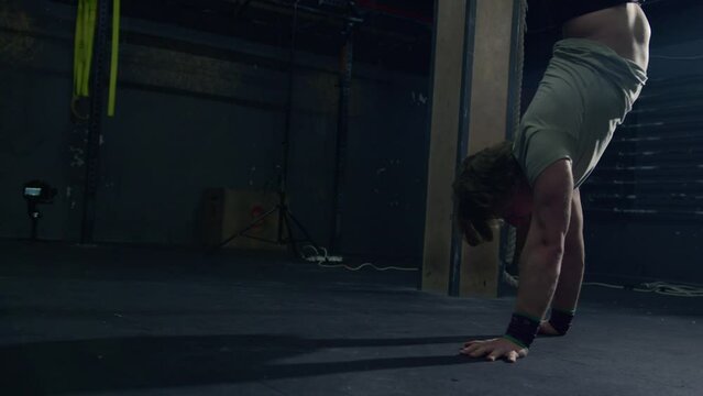 Man walking forward doing handstand in a Crossfit box. Crossfit exercise