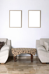 Mockup dos cuadros en pared blanca con dos sillones y una mesa con luz ambiental vertical