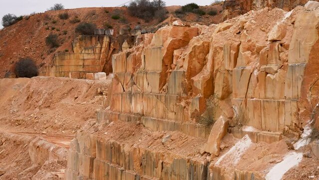 Limestone quarry mine with cut layered walls from removed blocks , Pan right shot