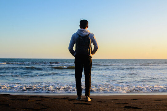 man standing on the seashore at sunset