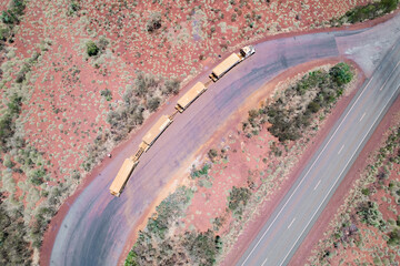 Looking down on a long truck known as a road train stopped at a truck resting area next to the asphalt road