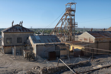 View of headframe and buildings at old mining site in Broken Hill, NSW, Australia with townscape in the background. This area of Broken Hill is where the mining company BHP was founded in 1885. 