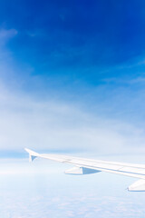 View from the airplane window at a beautiful cloudy sky and the airplane wing
