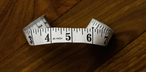 Close up of 60 inch tailor's tape measurer showing 4 to 6 inches and curled at each end. 