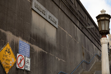 Stone wall next to stairs to Sydney Harbour Bridge cycleway in Sydney, New South Wales, Australia. Signs on wall prohibiting pedestrians to use the stairs.