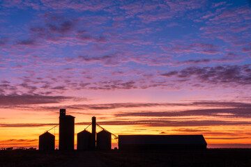 Colours of Dawn behind the Silhouettes of silos in a rural setting