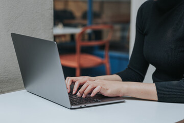 Female hands typing on laptop keyboard.