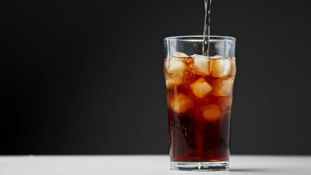 Drinking Coca Cola of Glass Cup with Ice and Wet Surface Close Up. Drink Sparkling Beverage or Diet Coke on Studio Shot in Macro. Eating of Colourful Pub Meal or Fast Food Isolated on Dark Background