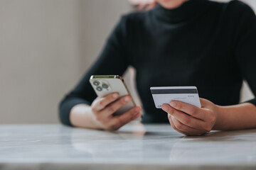 online payment Young woman's hand holding a credit card and using a smartphone for online shopping.