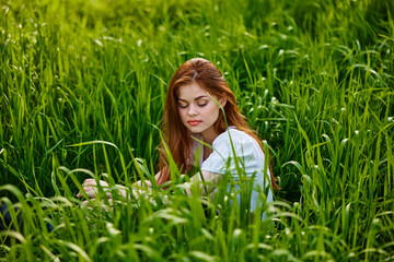 sad woman sitting in tall green grass on a sunny day