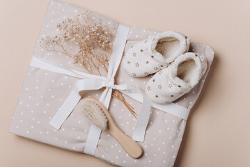 Newborn background. Baby muslin with bow, shoes, wooden brush, bib, eco teether, organic cotton crocketed toy in box. Baby linen and accessories. Gift for newborn baby. Top view. Copy space. Flat lay.