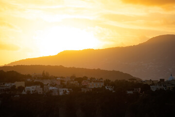 Houses of Procida in magic sunset with the island of Ischia in the background.
