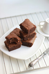 Homemade chocolate brownies stacked on a white plate, side and top view. Close-up.