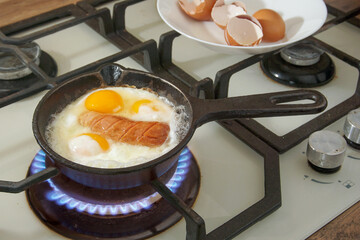 Fried eggs in a frying pan on a gas stove.