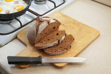  Rye bread with a knife and cut pieces of this bread lie on a cutting board next to the eggs in a...