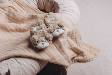 Soft baby shoes, booties on beige cocoon, baby nest for newborn over cribs in nursery. Childhood concept. Eco-friendly safe goods and toys for children. Light kid's room interior. Time for sleep