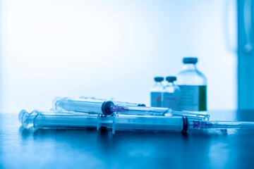 Blue tone of medical syringe, drug vial or ampule on table with light space background. Bottle of...