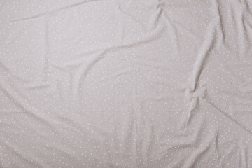 Top view of wrinkles on beige spotted bed sheet. Bed linen texture. Copy space