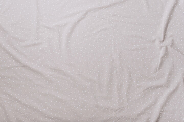 Top view of wrinkles on beige spotted bed sheet. Bed linen texture. Copy space
