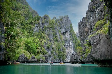 Majestic rocks in El Nido, Palawan in the Philippines that are overgrown with shrubs and rise out of the water.