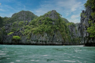 Fototapeta na wymiar Majestic rocks in El Nido, Palawan in the Philippines that are overgrown with shrubs and rise out of the water.