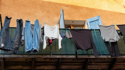 Clothes drying on a wooden balcony of an orange facade, Digne les Bains, Alpes de Haute Provence, France.