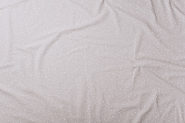 Top view of wrinkles on beige spotted bed sheet. Bed linen texture. Copy space