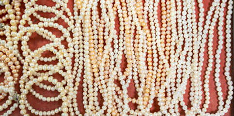 Natural sea pearls. A bunch of pearls on a red background, pearl strands close-up.