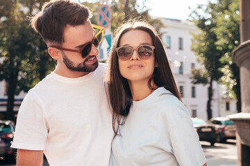 Smiling beautiful woman and her handsome boyfriend. Woman in casual summer jeans clothes. Happy cheerful family. Female having fun. Sexy couple posing in the street at sunny day. In sunglasses