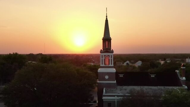 A parallax aerial establishing shot sunset view of a church steeple in Ocala, Florida.