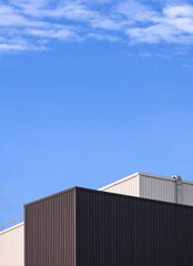 Modern Black and white corrugated iron factory buildings against cloud on blue sky background in vertical frame, low angle view with copy space
