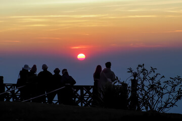 Fototapeta na wymiar asians travel relax in the holiday.People stand looking at the sun in the morning. Stand up for sunrise on the Moutain