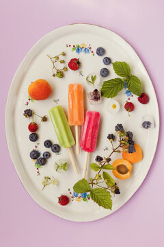 Colorful popsicles on tray with berries