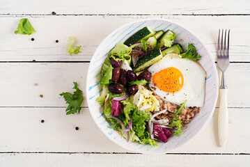 Breakfast wheat porridge with  roasted egg, cucumber and olives. Healthy balanced food. Top view, flat lay