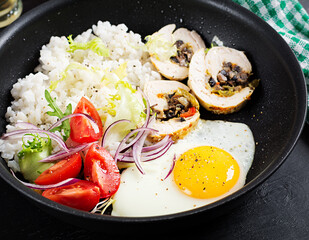 Fried egg, meat chicken roll, rice and tomatoes. Paleo breakfast.