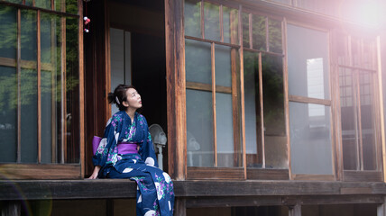 Woman in yukata sitting on the porch in summer looking up at the sky