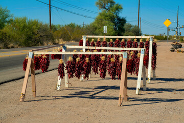 Hanging dried or dehydrated chili pepper wreaths available for sale on side of road or street on wooden horse stand