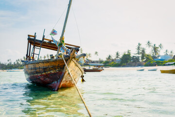 Fototapeta premium Experience the beauty of a traditional Zanzibar fishing boat as it rests in the clear waters near the beach of a tropical island, ideal for summer travel and fishing boats.