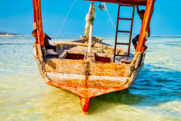Experience the beauty of a traditional Zanzibar fishing boat as it rests in the clear waters near...
