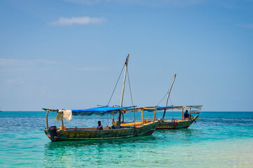 Fototapeta na wymiar Experience the beauty of Zanzibar's tropical coast from a bird's eye view, with fishing boats resting on the sandy beach at sunrise. The top-down perspective showcases clear blue waters, green palm 