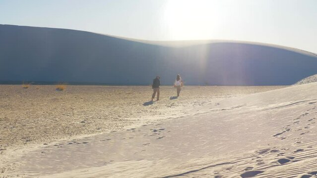 Male and Female couple walking hiking sand dunes desert landscape at white sands national park in New Mexico