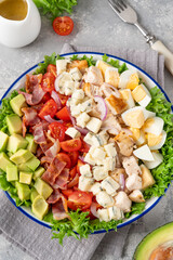 Tradition Cobb salad with fried chicken, avocado, fresh tomatoes, eggs, bacon and cheese on a plate. selective focus