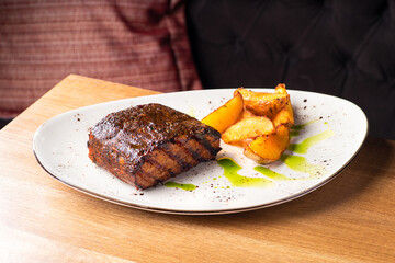 Gourmet Main Dish with Grilled Pork Rib and Fried Potatoes on White Plate. S