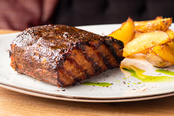 Close up Gourmet Main Dish with Grilled Pork Rib and Fried Potatoes on White Plate. S