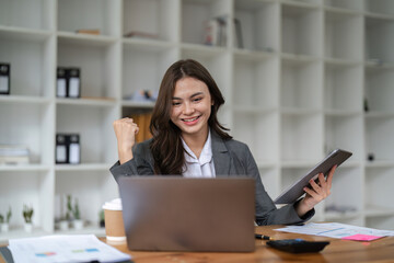 Happy woman office worker feeling excitement raising fists celebrates career ladder promotion or reward, businesswoman sitting at desk receive online news, great results successful work concept