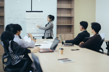 Young beautiful business woman giving flipchart presentation to coworkers during meeting , explain goals strategy at team meeting workshop. 