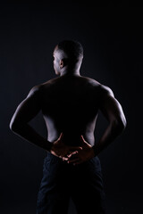 Naklejka premium One young african muscular build man standing topless silhouette isolated on black background
