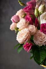 A bouquet of bushy roses of light pink and fuchsia color on a dark gray blurred background